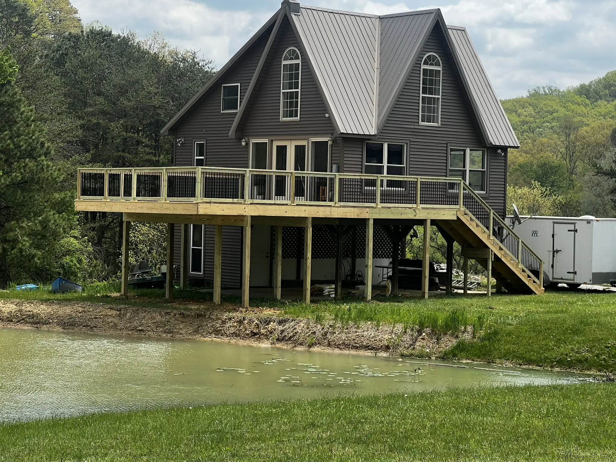 A finished elevated deck on a chalet-style home overlooking a pond